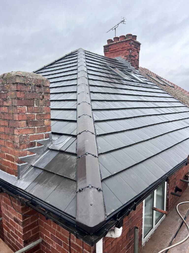 After: new grey tiled roof in Worksop with chimney stack, Velux roof windows and angled grey ridge tiles
