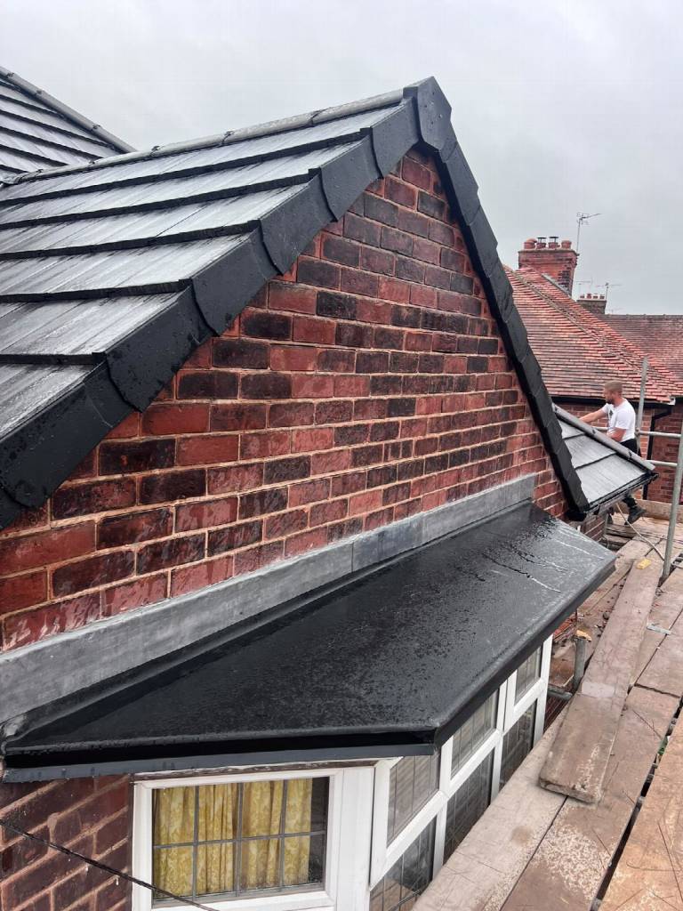After: gable end with black dry verge capping, new grey roof tiles and a new flat roof section on the Worksop property